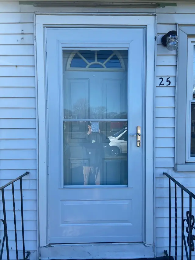 A newly installed white storm door on a shingled Connecticut home, fitted by The Renaissance Handyman